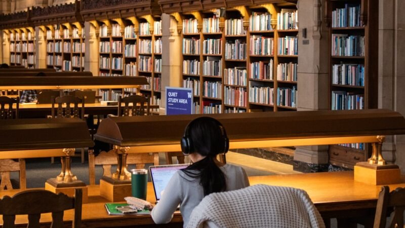Student studying with a laptop in a library, representing an AI homework-helper app