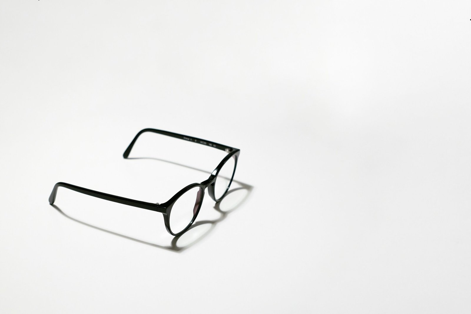 Black framed eyeglasses on a white surface, no camera lens visible