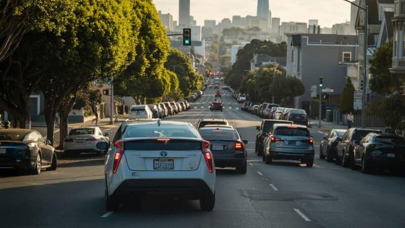 Cars driving down a downtown city street toward the skyline, representing ride-hailing traffic