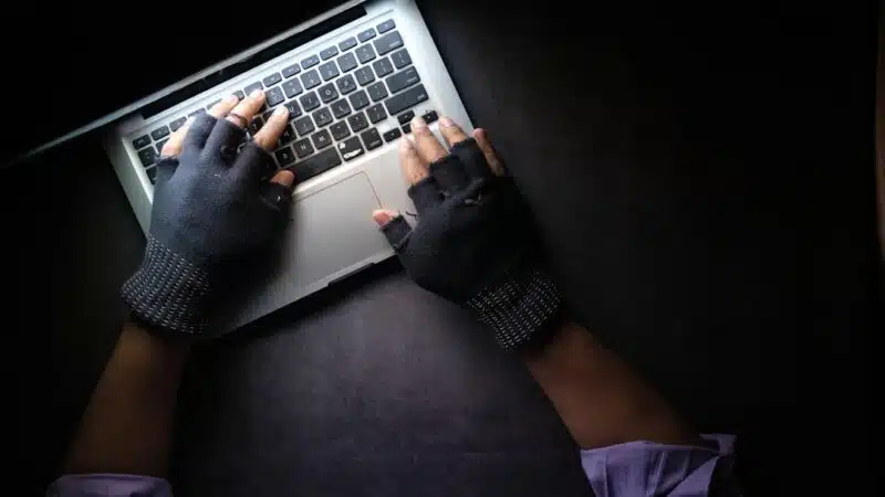 A hand reaching toward a laptop keyboard, representing the risk of ClickFix malware attacks tricking users