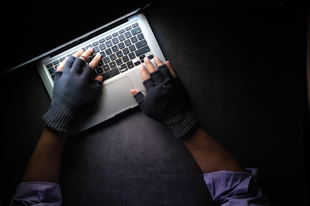 A hand reaching toward a laptop keyboard, representing the risk of ClickFix malware attacks tricking users