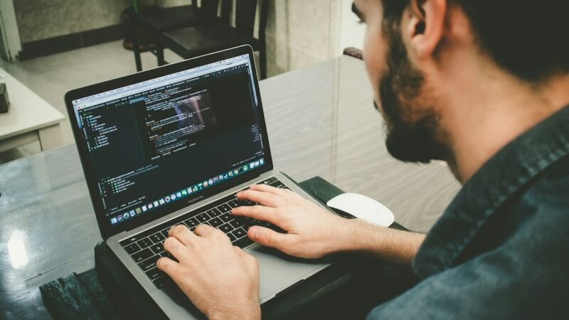 Developer typing code on a laptop, representing AI coding assistants