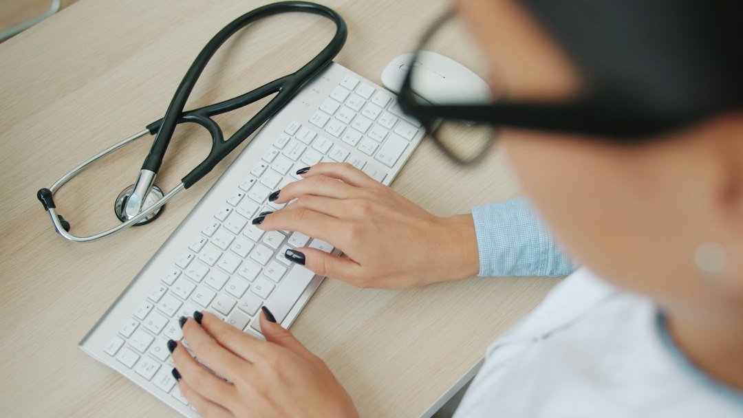 Doctor typing on a computer using electronic health records software, representing AI documentation tools in hospitals