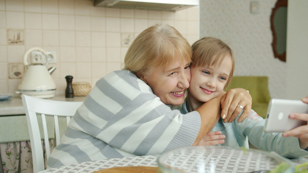 Family members using a smartphone together at a kitchen table