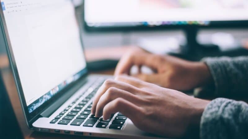 Writer's hands typing on a laptop keyboard, representing content publishers affected by Google's AI answer features
