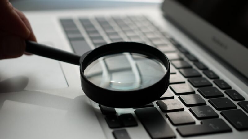 Magnifying glass over a search page on a laptop, representing changes to Google Search and AI Mode