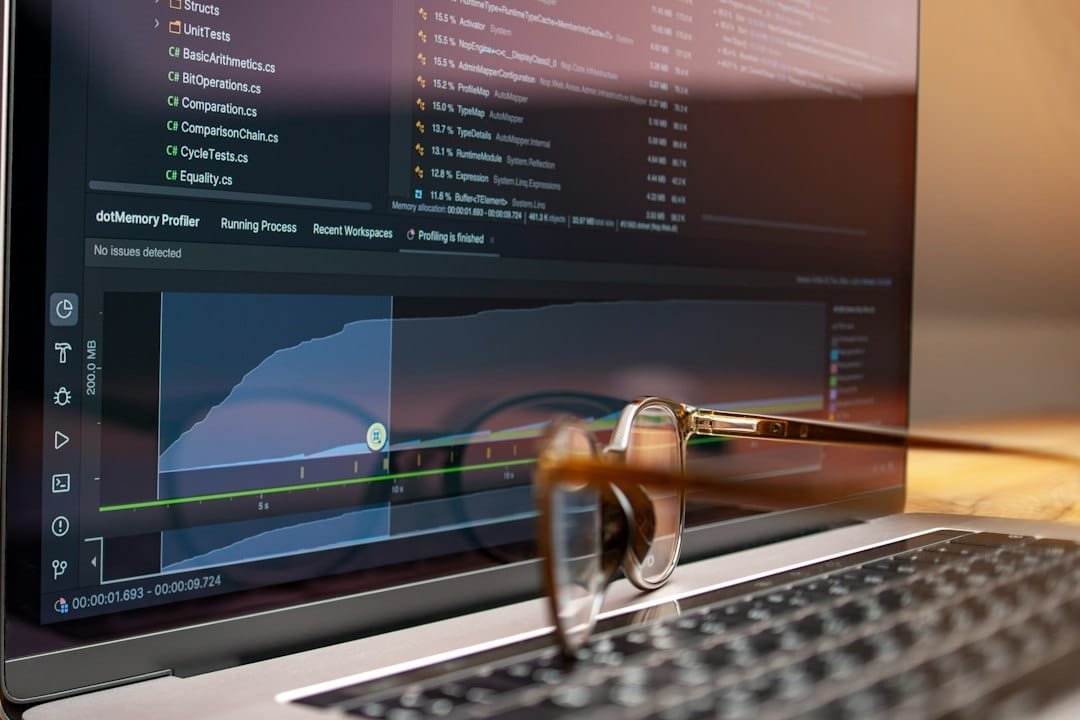A laptop displaying data graphs with a pair of glasses resting on the keyboard