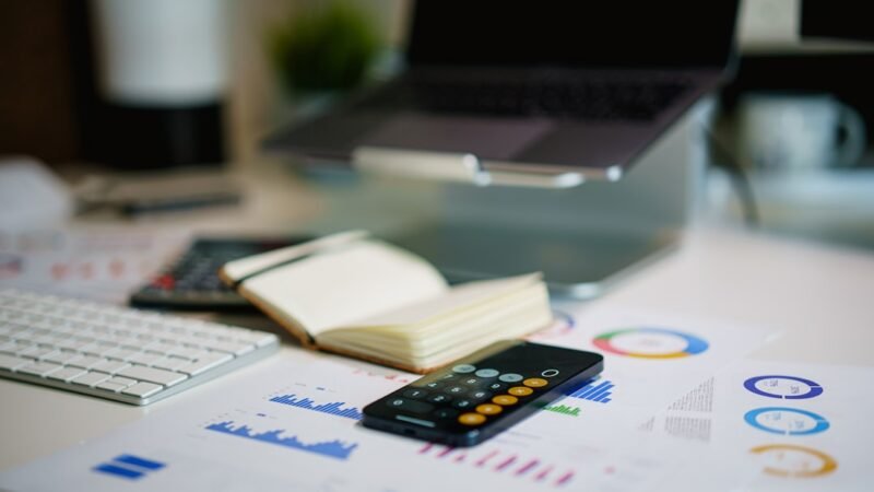 Laptop displaying financial data charts and graphs on a desk