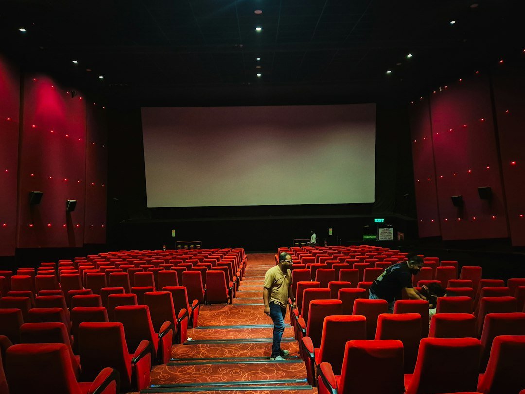 Movie theater screen in a dark cinema, representing the theatrical release of the Musk documentary