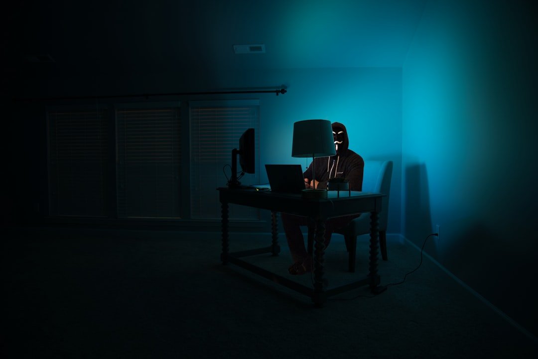 Person at a computer wearing an anonymous mask, representing state-backed hacking group WaterPlum