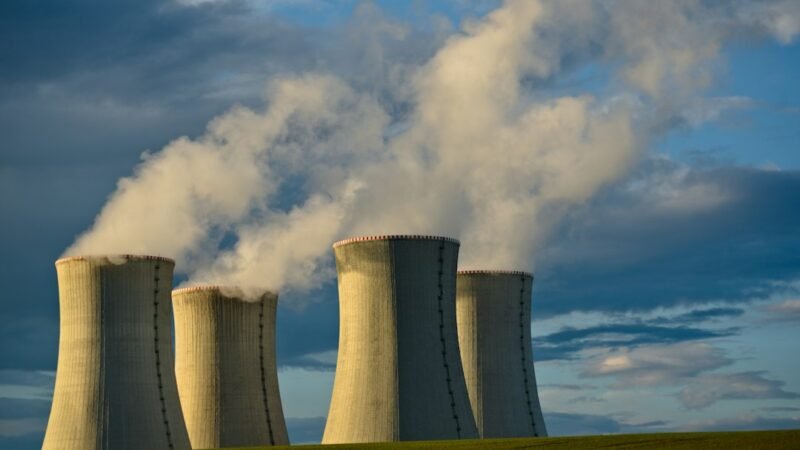 Nuclear power plant cooling towers under a blue sky, representing new nuclear investment for data centers