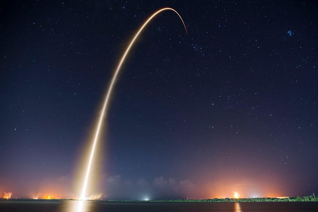 Long exposure of a rocket launch arcing over dark water at night
