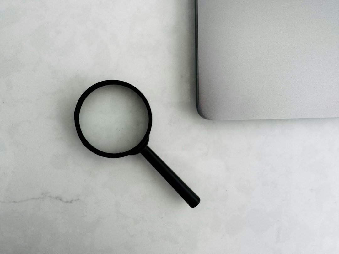 Magnifying glass beside a laptop on a desk, illustrating search engine monitoring tools