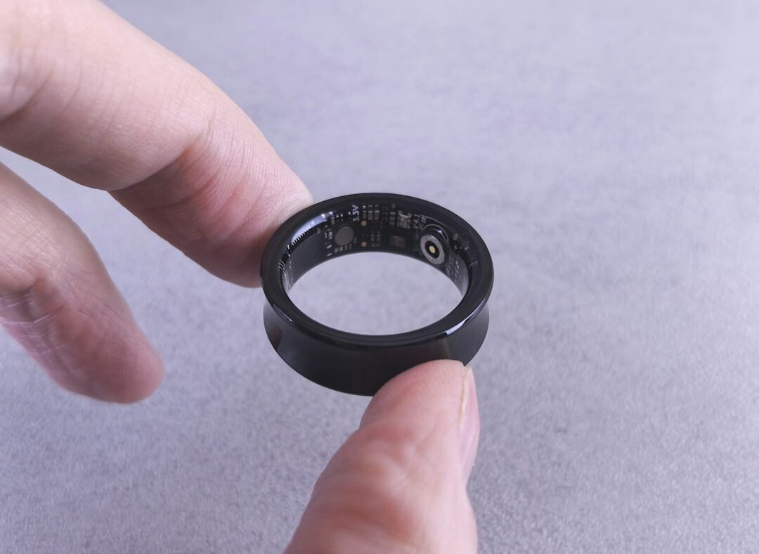 A smart ring held between fingers, representing the wearable device category Oura leads ahead of its IPO