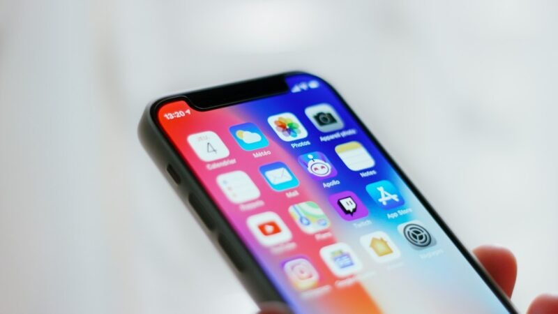 Person holding a smartphone showing a home screen of apps