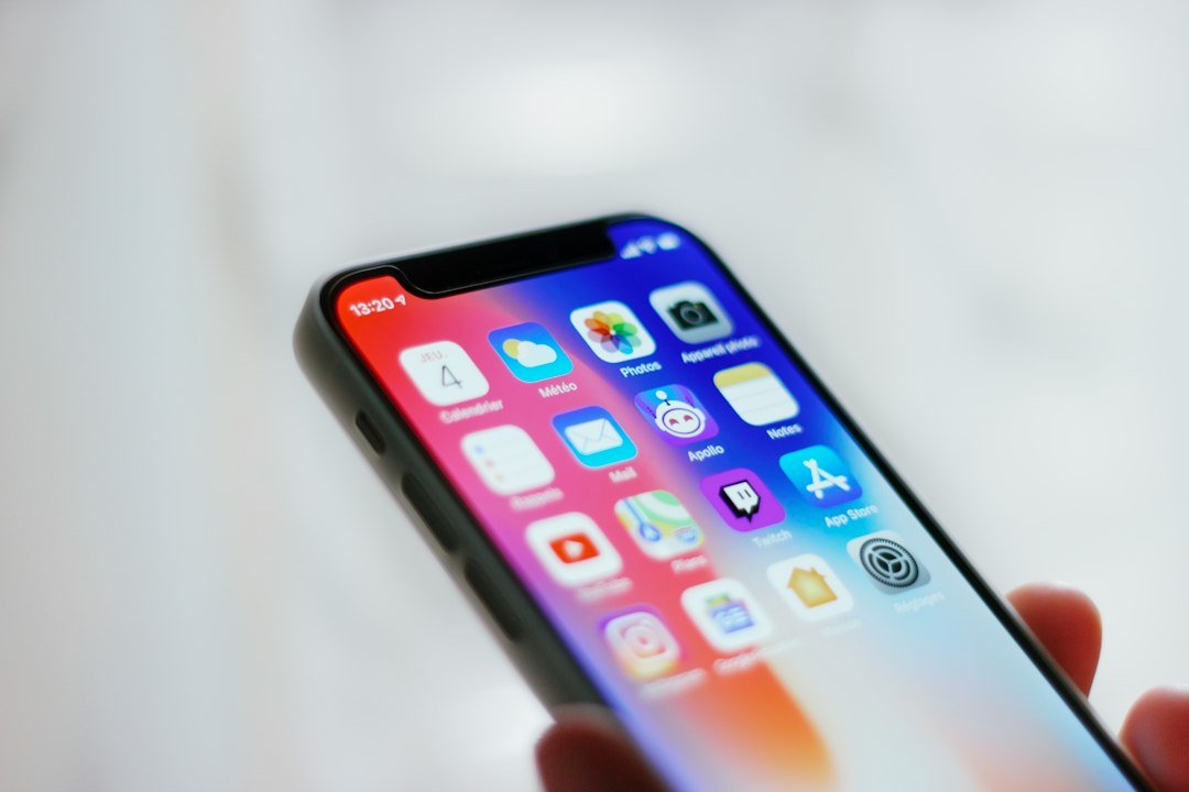 Person holding a smartphone showing a home screen of apps