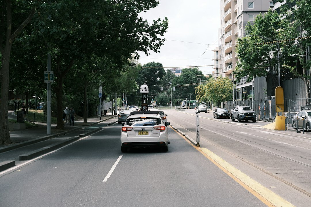 Car driving down a city street next to tall buildings, illustrating urban autonomous driving