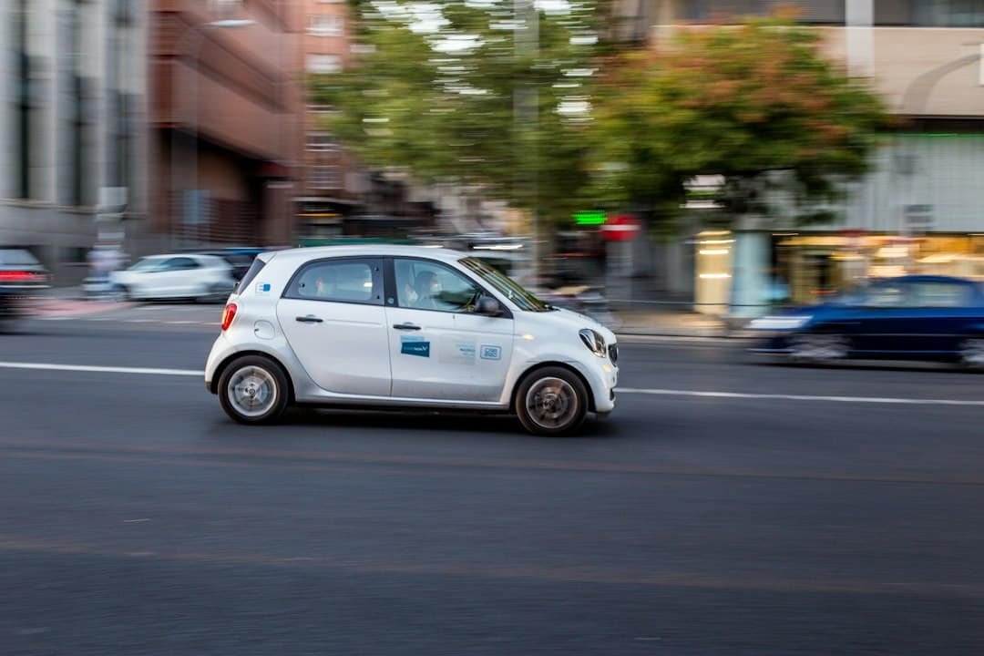 A white SUV style vehicle driving on a city road in daytime