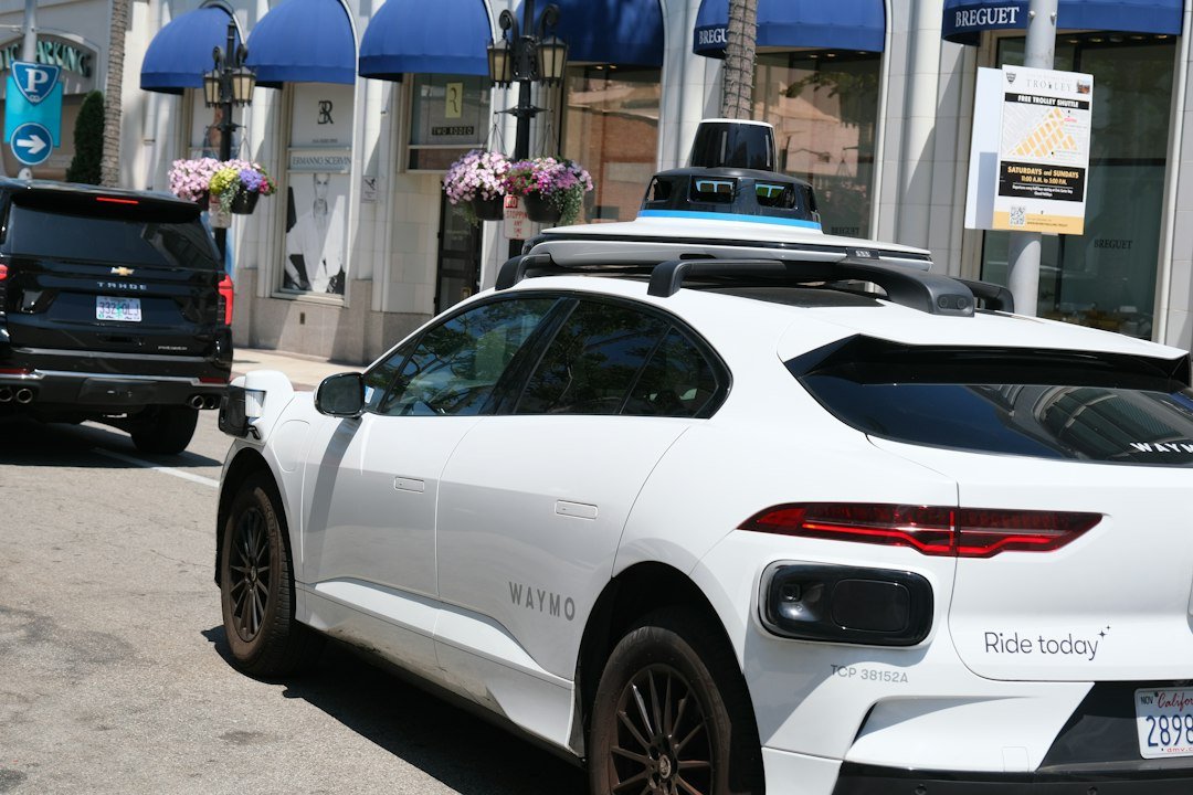 A white Waymo autonomous vehicle with roof sensors parked on a city street