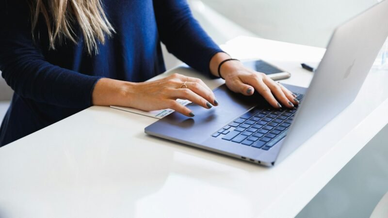 Person typing and editing a document on a laptop, representing AI paraphrasing and writing tools