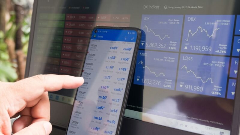 Trading charts on smartphones and laptops, representing X's new Cashtag stock trading feature