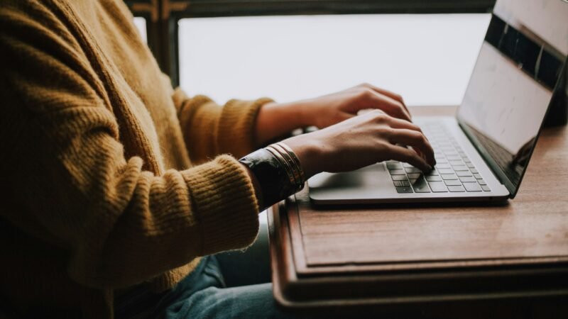 Content marketer typing on a laptop with coffee, researching and writing a blog article