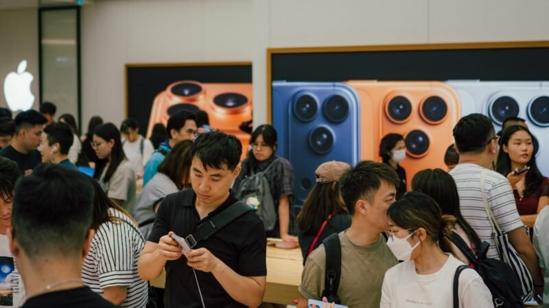 Crowd of customers inside an Apple Store on a product launch day, trying new devices on display tables