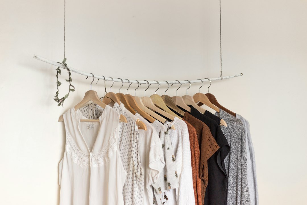 Assorted clothes hanging on wooden hangers in a closet