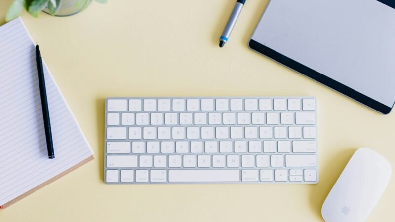 Flat lay of a desk with a laptop, tablet, and keyboard