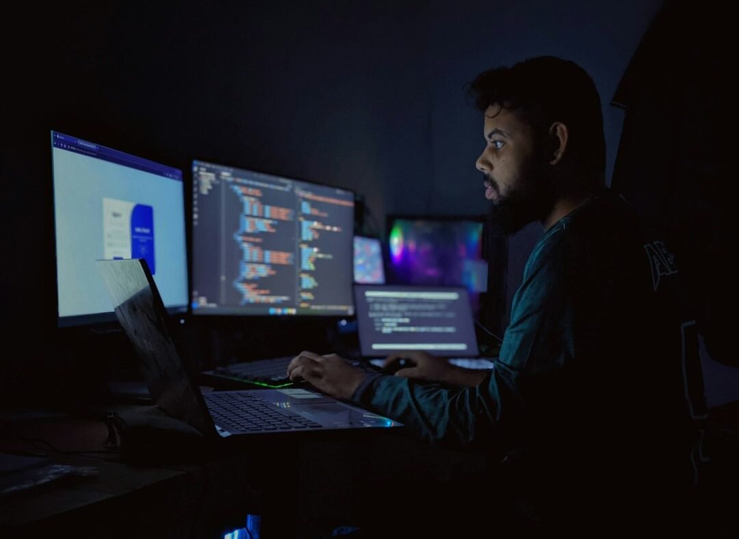 Developer working late with multiple code screens