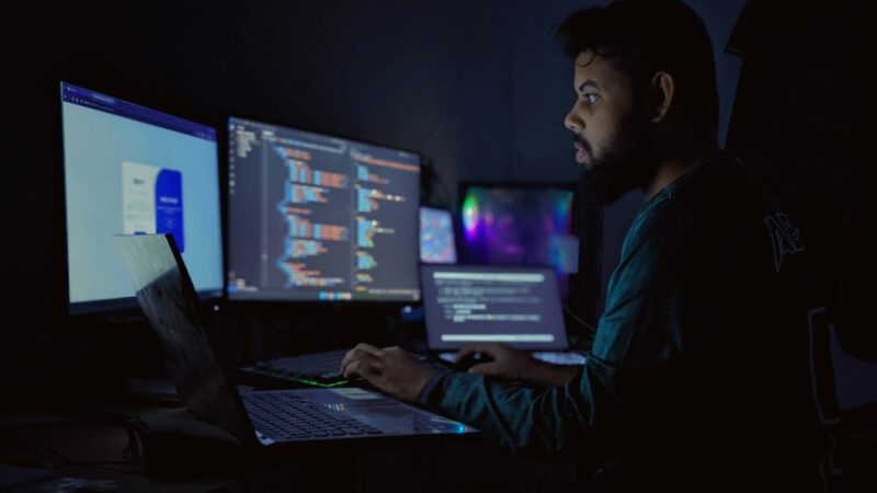 Developer working late with multiple code screens