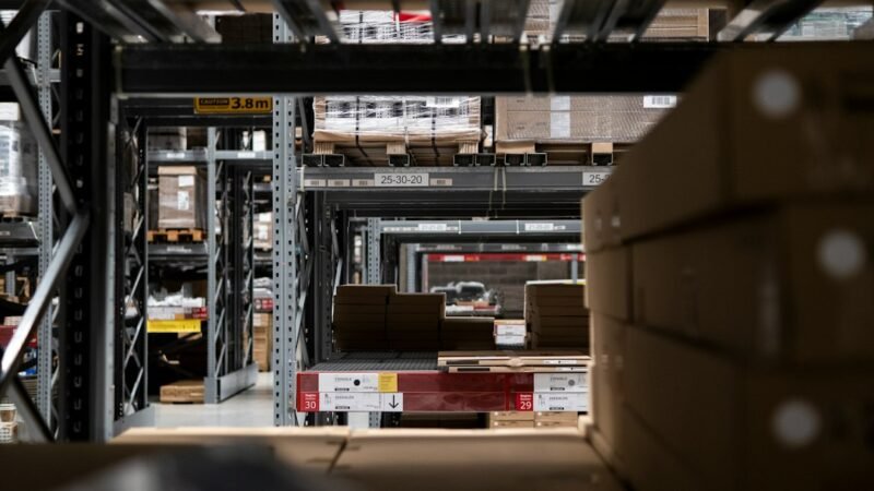 Warehouse filled with stacked shipping boxes, representing e-commerce fulfillment and AI shopping agents
