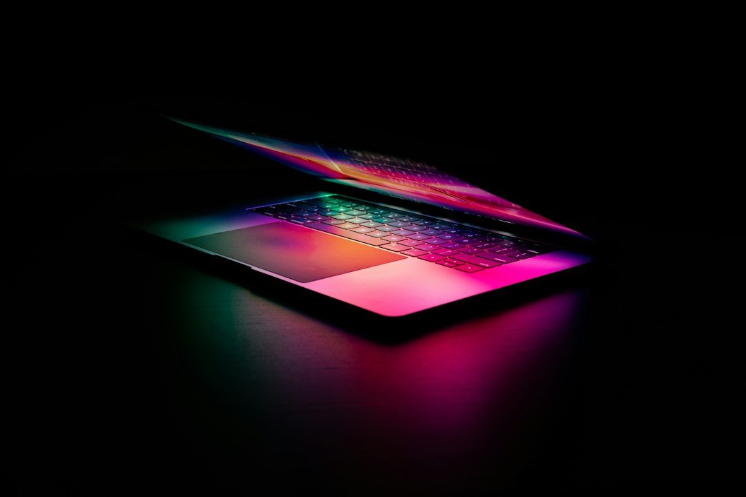 A laptop keyboard glowing with pink and green light, representing AI search technology