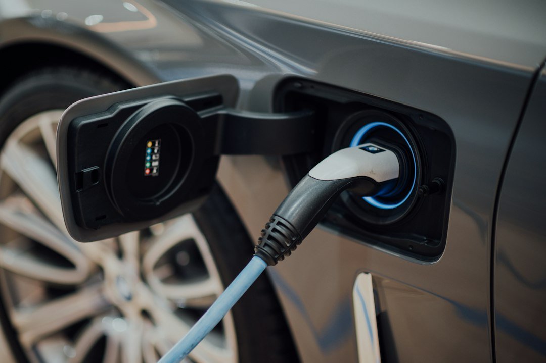 An electric vehicle charging cable plugged into a car at a charging station