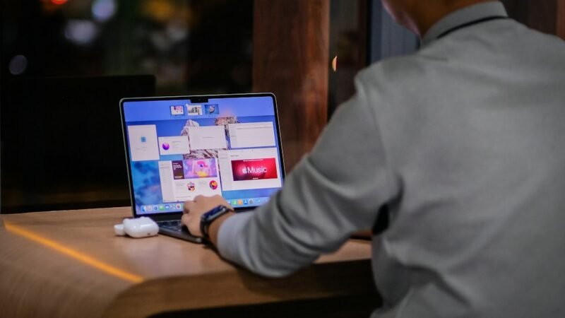 Entrepreneur working late on a laptop with a city skyline behind, illustrating the modern hustler meaning