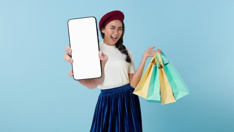 A woman holding a tablet computer and shopping bags, representing online clothes shopping