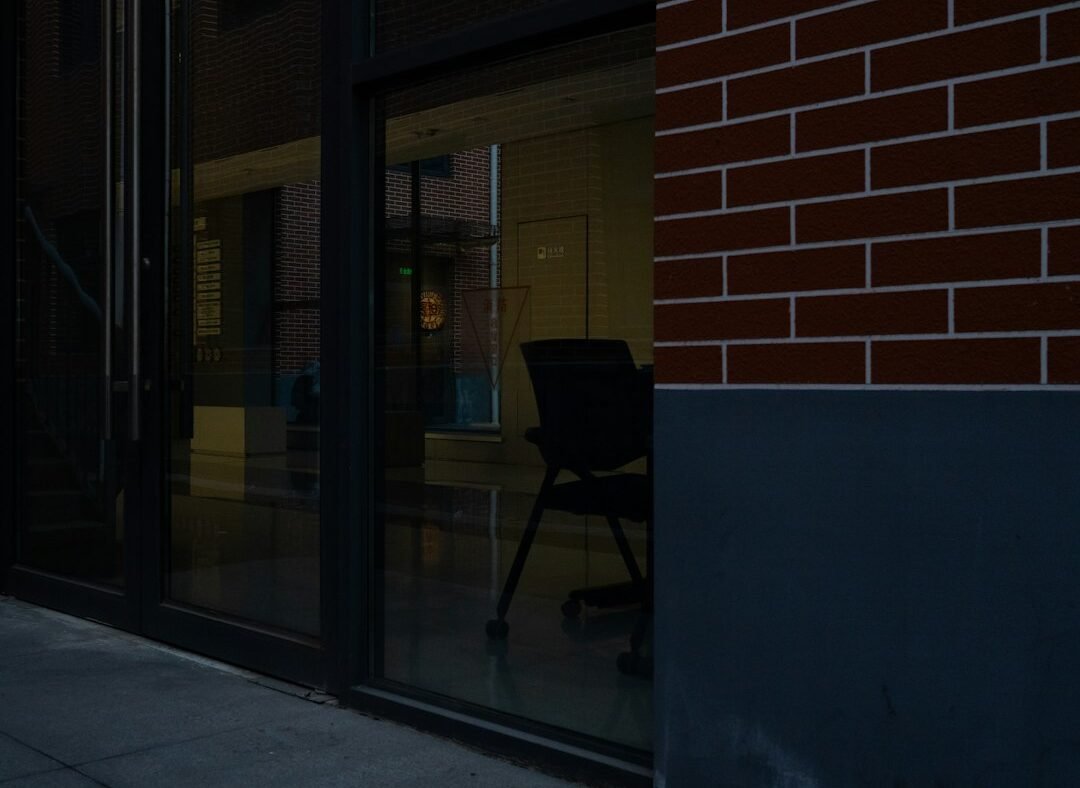 Empty office chair reflected in a glass office building, representing an employee departure