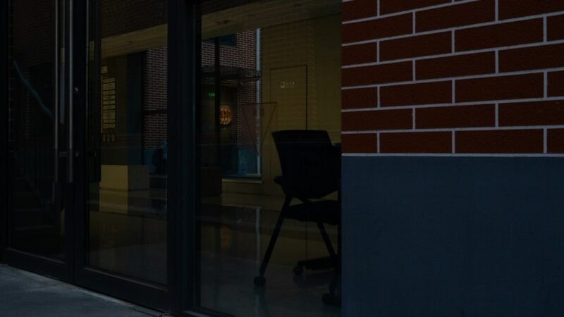 Empty office chair reflected in a glass office building, representing an employee departure