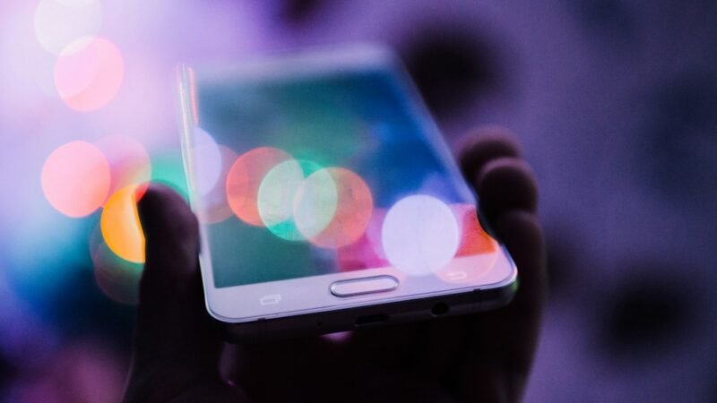 A person holding a smartphone, representing rising consumer device prices