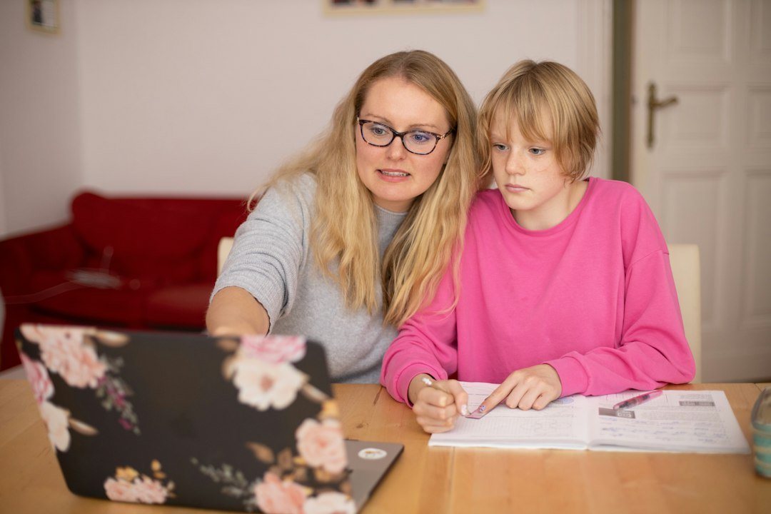 Mom working on a laptop next to her child, fitting a side hustle around family time