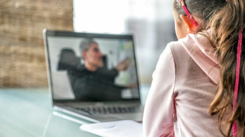 Teacher tutoring a student online on a laptop as an evening side hustle