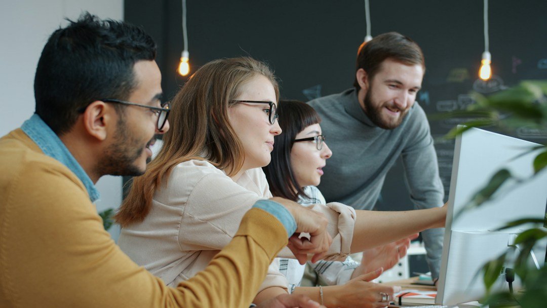 Team discussing AI deployment plans around a computer screen in a modern office