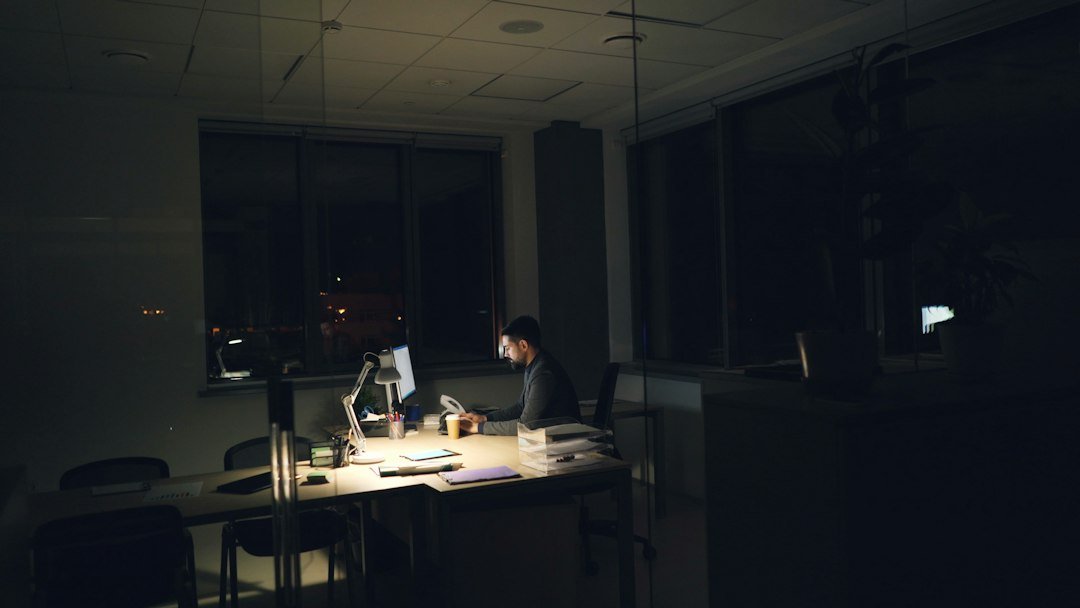 Tired office worker at a desk late at night, illustrating hustle culture and long working hours