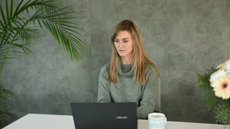 Woman working on a laptop in a home office on a side hustle