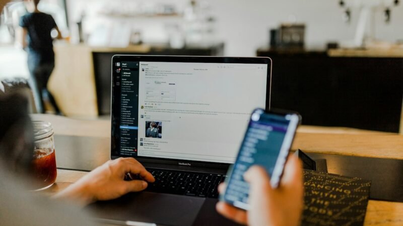 Team members messaging each other on phones and laptops in a modern workplace
