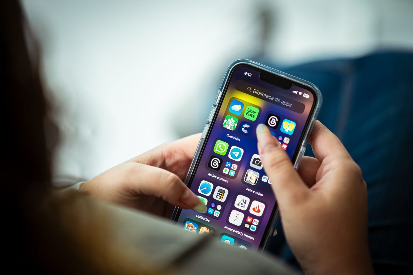 Woman holding a smartphone showing various apps