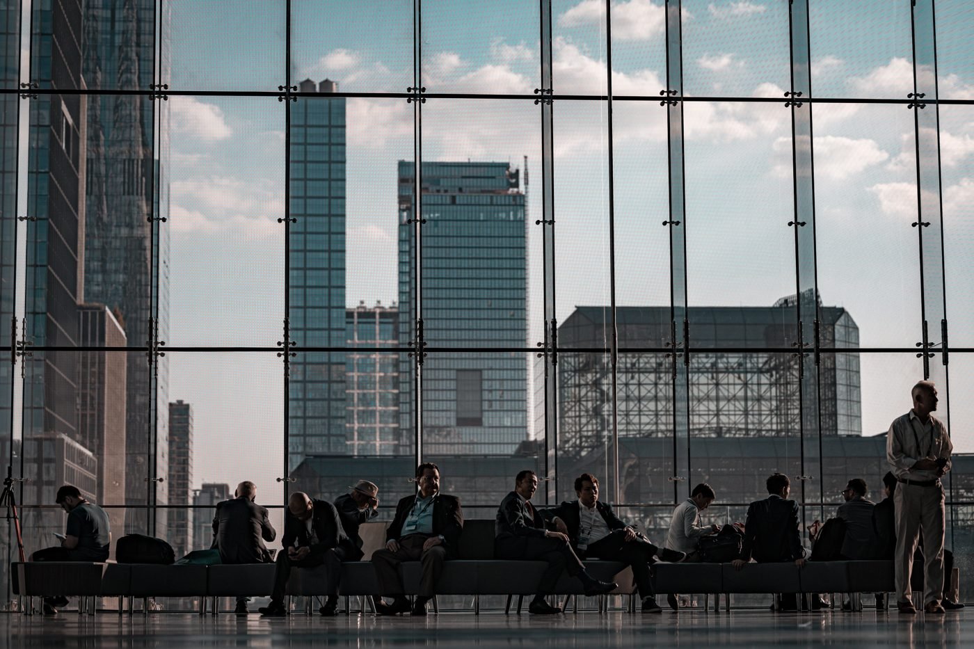 Business professionals in a glass-walled hall with a city skyline behind them