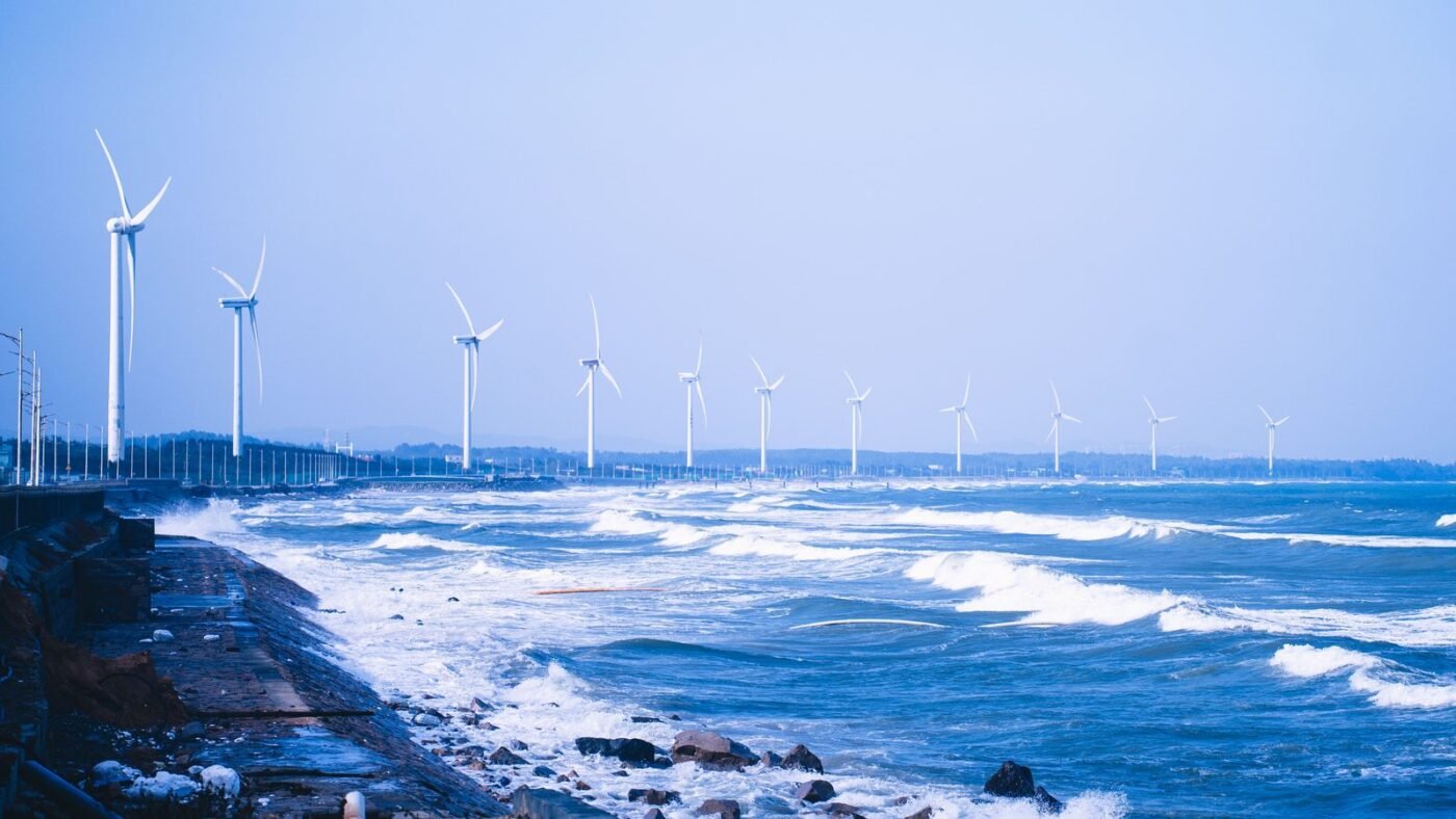 Coastal wind farm with turbines beside the ocean under a clear blue sky