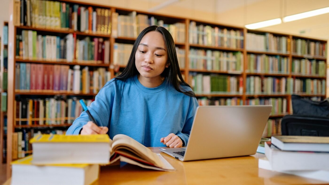 Student studying with a laptop and books in a library