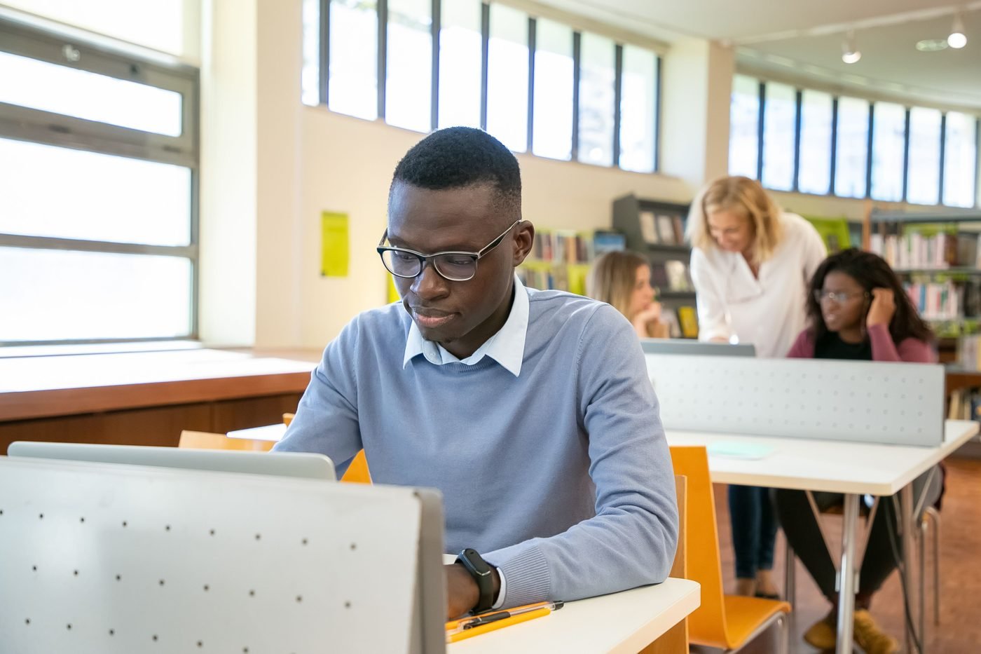 Group of students studying together with laptops in a library